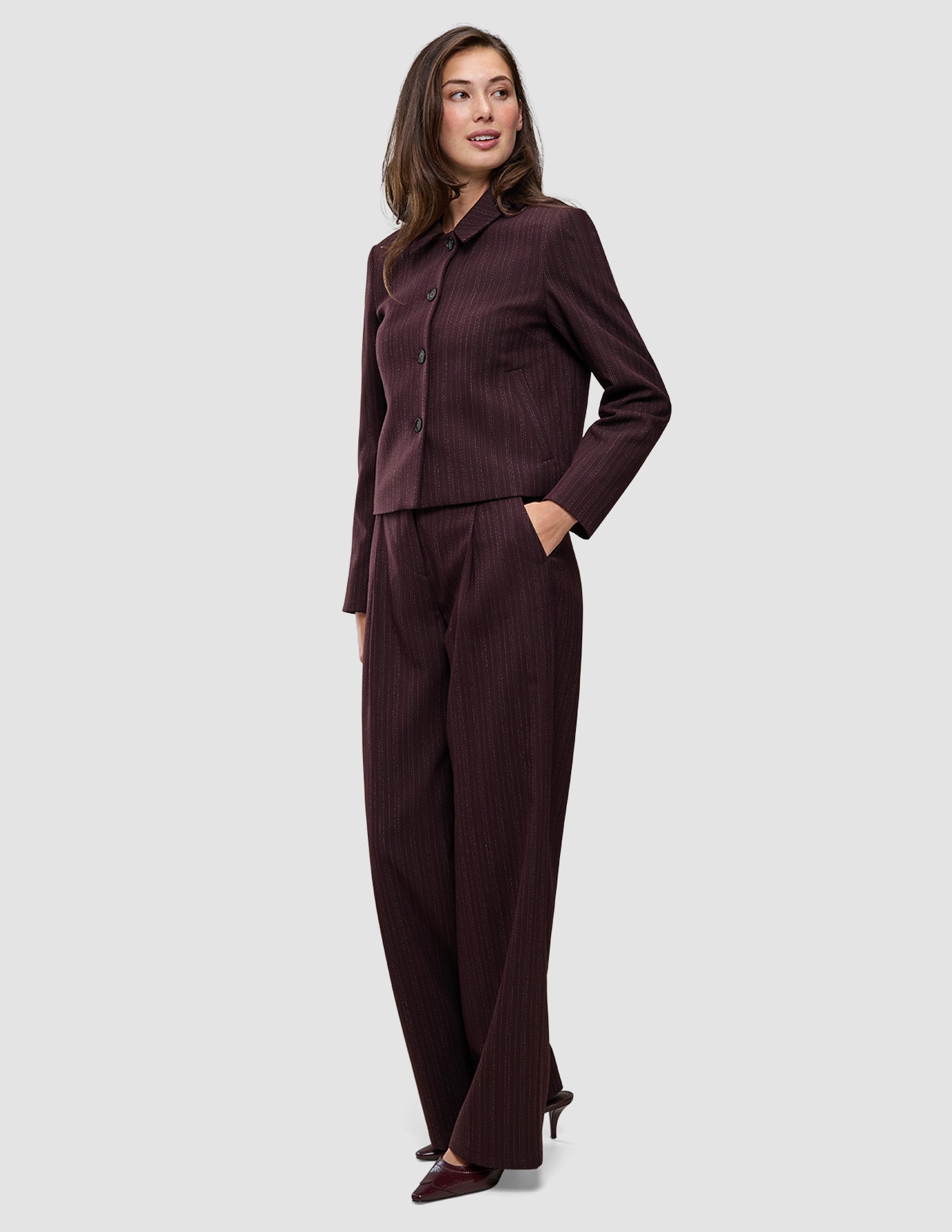 En kvinde bærer den korte jakke Women Serene Short Jacket Berry Pinstripe og de tilhørende bukser, der fremhæver det elegante danske design.